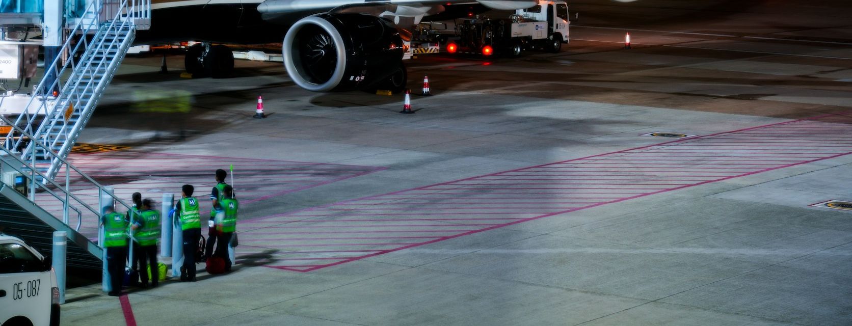 Ground crew in high-visibility vests beside an aircraft at night